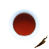 A cup of brewed Boseong Korean Black, next to brewed tea leaves