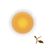 A cup of brewed Bulang Bamboo Raw Pu-erh, next to brewed tea leaves