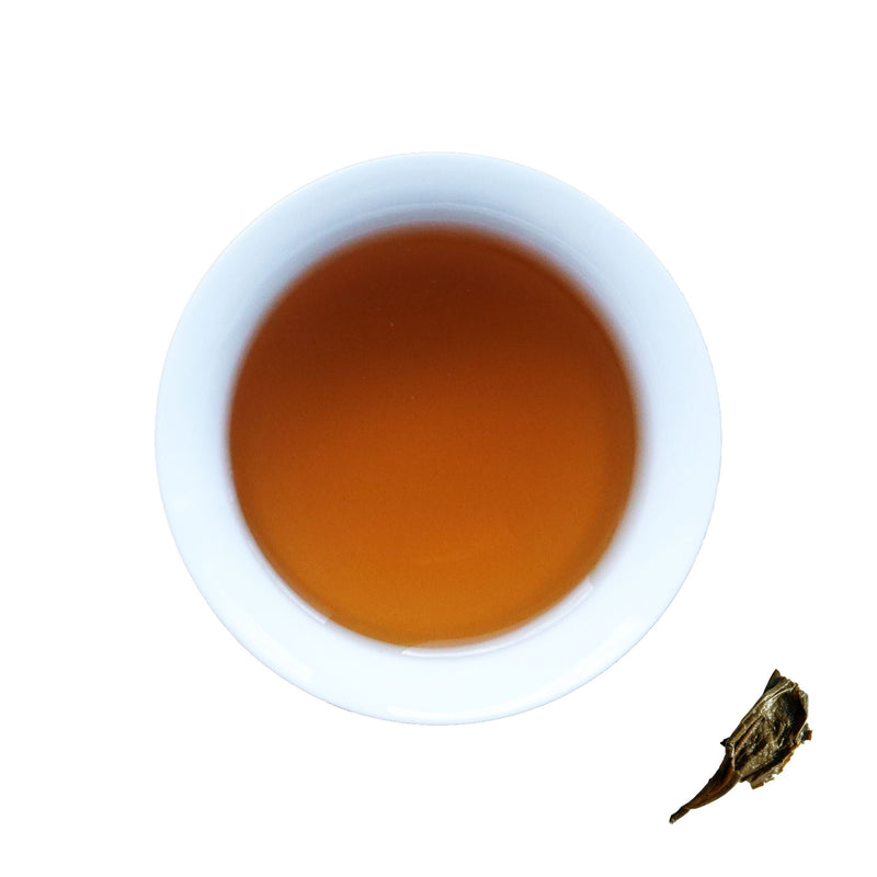 A cup of brewed Golden Flower, next to brewed tea leaves